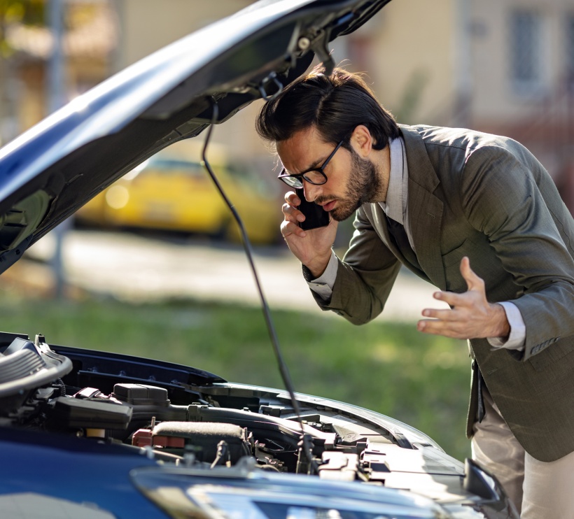 Człowiek stojący w pobliżu rozbitego samochodu i dzwoniący